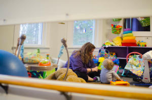 A woman playing with a child in a classroom