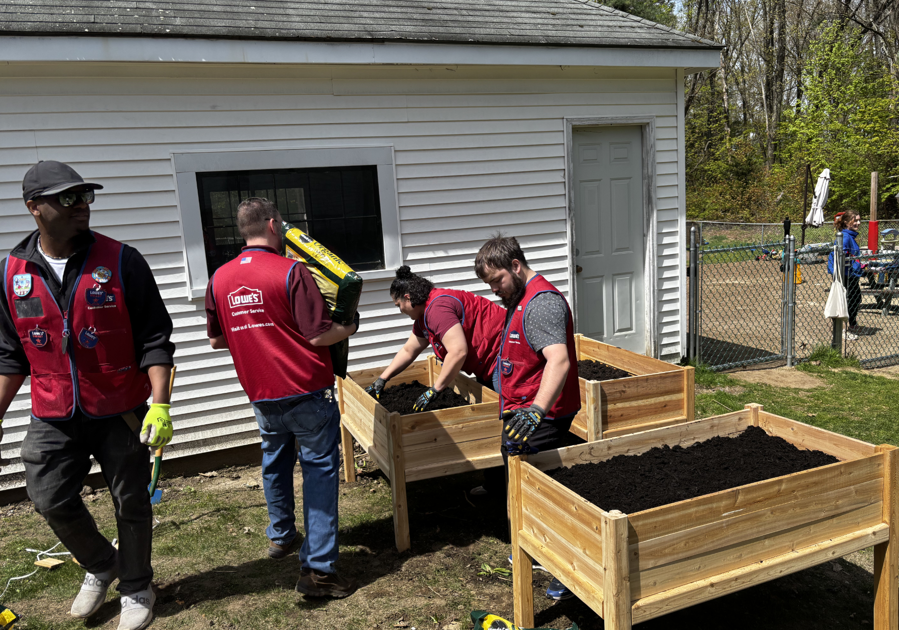 Four workers wearing red vests building a series of raised planting beds.